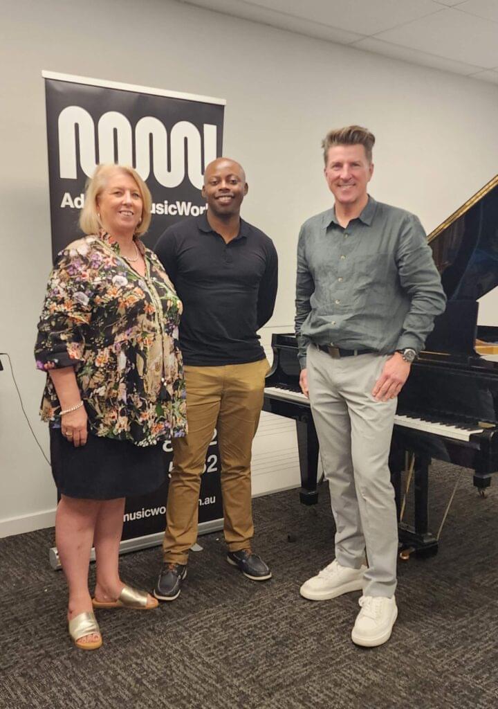 Three people standing beside grand piano